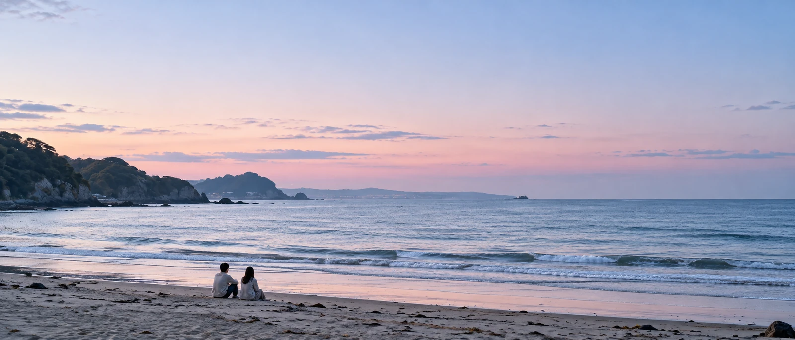 夕方の浜に座るふたりの後ろ姿と、淡い桃色の空